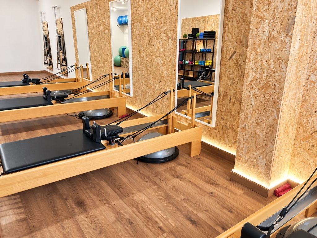 Máquinas Reformer junto a la pared de madera iluminada en el centro Campreciós de Pilates Esplugues